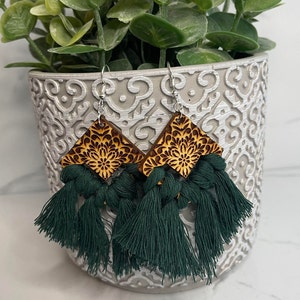 May include: A pair of wooden earrings with a geometric design and green tassel fringe.