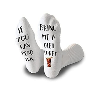 May include: White socks with black text that reads "IF YOU CAN READ THIS" on one sock and "BRING ME A DIET COKE!" on the other. A graphic of a Diet Coke glass is also printed on the second sock.