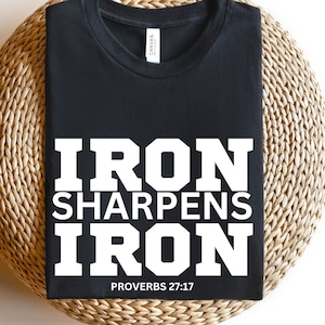 May include: Black t-shirt with white text that reads "Iron Sharpens Iron" and "Proverbs 27:17".