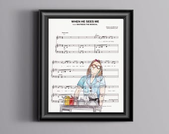 Puede incluir: Una impresión enmarcada de partituras para la canción "When He Sees Me" del musical "Waitress." La música está escrita en tinta negra sobre papel blanco. Una ilustración dibujada a mano de una mujer con uniforme azul y gafas se encuentra en el centro de la página.