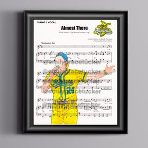 May include: Framed print of sheet music for "Almost There" from Disney's "The Princess and the Frog." The artwork features a cartoon illustration of a performer in a yellow baseball uniform with the number 24, singing into a microphone.
