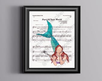 May include: Framed print with sheet music and a teal mermaid tail illustration. The mermaid has red hair and holds a fork. The text "Part of Your World" is visible, along with musical notes and lyrics.