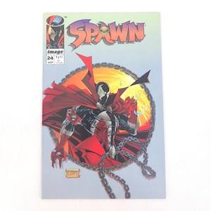 May include: Spawn comic book, issue 24, featuring a detailed illustration of the Spawn character with a red cape, chains, and a circular background. The comic cover has the Spawn logo and the Image Comics logo.