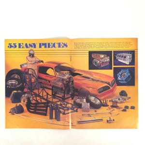 May include: An open magazine spread with the title "55 Easy Pieces" features an orange dragster car with various disassembled parts. A person in a racing suit stands near the car. The image includes engine components, tires, and a chassis, all set against a yellow background.