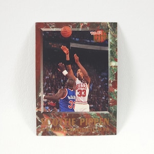 May include: A basketball trading card featuring Scottie Pippen of the Chicago Bulls. Pippen, wearing jersey number 33, is shown shooting a basketball over an opposing player. The card has a marbled border and the text "'92-'93" and "Scottie Pippen".
