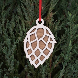 May include: White wooden Christmas ornament shaped like a hop cone with a red ribbon attached.