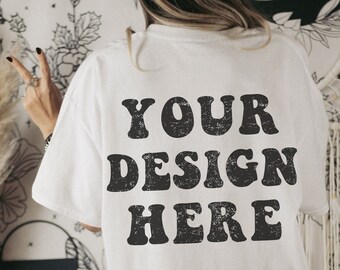 May include: White t-shirt with the text "YOUR DESIGN HERE" printed in black on the back.