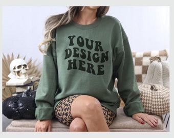 May include: A green sweatshirt with the text "YOUR DESIGN HERE" in black lettering. The sweatshirt is worn by a person with long brown hair and is sitting on a bench with a leopard print skirt.
