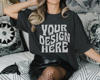 May include: A black t-shirt with the text "YOUR DESIGN HERE" in a retro font. The shirt is being worn by a person with long blonde hair and a black leather skirt.