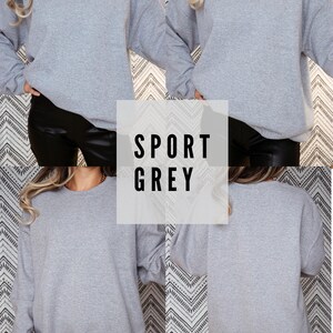Puede incluir: Una sudadera gris con el texto "SPORT GREY" impreso en ella. La sudadera se muestra en una modelo que lleva pantalones negros.