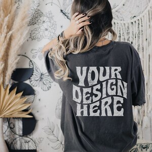 Puede incluir: Una camiseta gris oscuro de gran tama&ntilde;o con el texto "YOUR DESIGN HERE" impreso en blanco en la parte posterior.