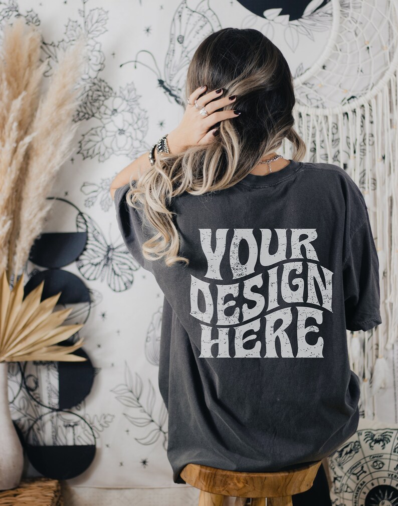 Puede incluir: Una camiseta gris oscuro de gran tama&ntilde;o con el texto "YOUR DESIGN HERE" impreso en blanco en la parte posterior.