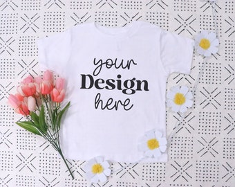 May include: White t-shirt with short sleeves and a crew neck. The shirt has the text "your Design here" printed on the front in black.