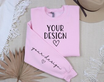 May include: A pink sweatshirt with the text "YOUR DESIGN" and a small heart on the front. The text "your design" and a heart are also on the sleeve.
