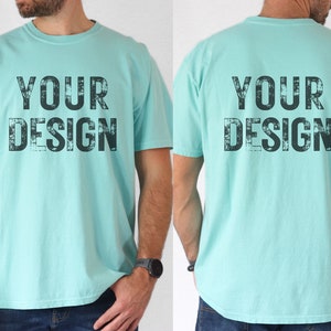 May include: A light blue t-shirt with the text "YOUR DESIGN" printed in black on the front and back. The text has a distressed, vintage look.