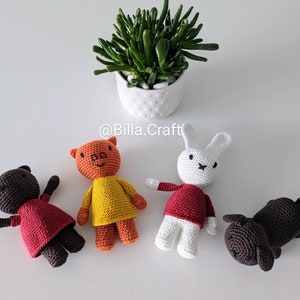 Peut inclure: Quatre animaux en peluche crochetés à la main : un ours brun dans une robe rouge, un cochon orange dans une chemise jaune, un lapin blanc dans une chemise rouge et un chien brun. Une petite plante succulente en pot est en arrière-plan. Le nom de la boutique Etsy "@Billa.Craft" est visible.