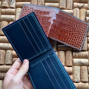 Puede incluir: Dos carteras de cuero, una azul con costuras turquesa y otra marr&oacute;n con costuras marrones. Ambas carteras est&aacute;n cerradas y tienen varias ranuras para tarjetas.