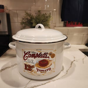 May include: A white ceramic mug with a black handle and the text "But First, Coffee" in a handwritten style. The mug is on a white surface. The mug is likely for hot beverages.