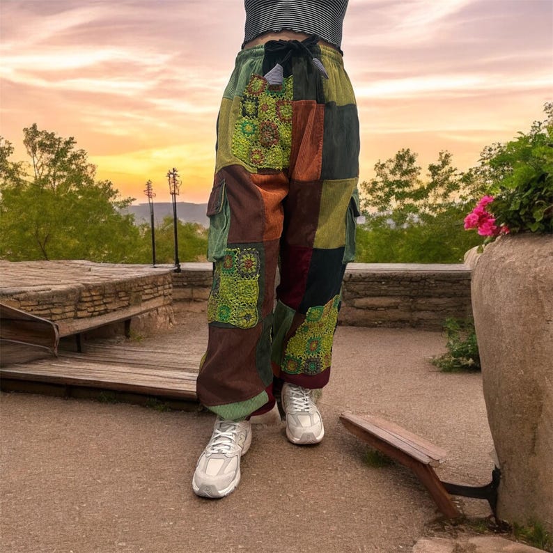 Puede incluir: Pantal&oacute;n cargo de patchwork con cintura de cord&oacute;n y varios bolsillos. El pantal&oacute;n est&aacute; hecho de una variedad de telas en tonos de marr&oacute;n, verde y rojo. El pantal&oacute;n lo lleva puesto una persona que est&aacute; de pie en un camino de piedra.