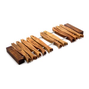 Könnte beinhalten: Holz-Topfuntersetzer mit Fischdesign. Der Untersetzer besteht aus hellem und dunklem braunem Holz, mit fischförmigen Teilen, die durch Metallstangen verbunden sind. Ein Küchenaccessoire zum Schutz von Oberflächen.