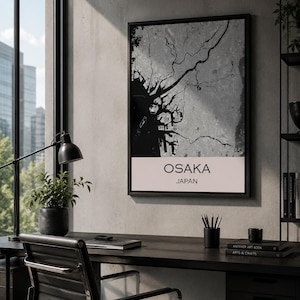 Könnte beinhalten: Ein gerahmter Wandkunstdruck mit einer schwarz-grauen Karte von Osaka, Japan. Der obere Bereich zeigt den geografischen Grundriss der Stadt in hohem Kontrast, während der untere weiße Bereich den Text OSAKA JAPAN in einer serifenlosen Schrift enthält.