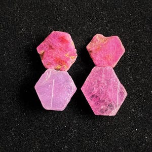 以下が含まれることがあります： 2組のピンクのルビーの宝石。それぞれが六角形で、わずかに異なるピンクの色合いをしています。