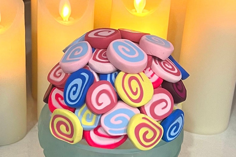May include: A pile of colorful, swirled clay pieces in various shades of pink, blue, yellow, and red. The clay pieces are arranged in a mound, creating a visually appealing and textured display.