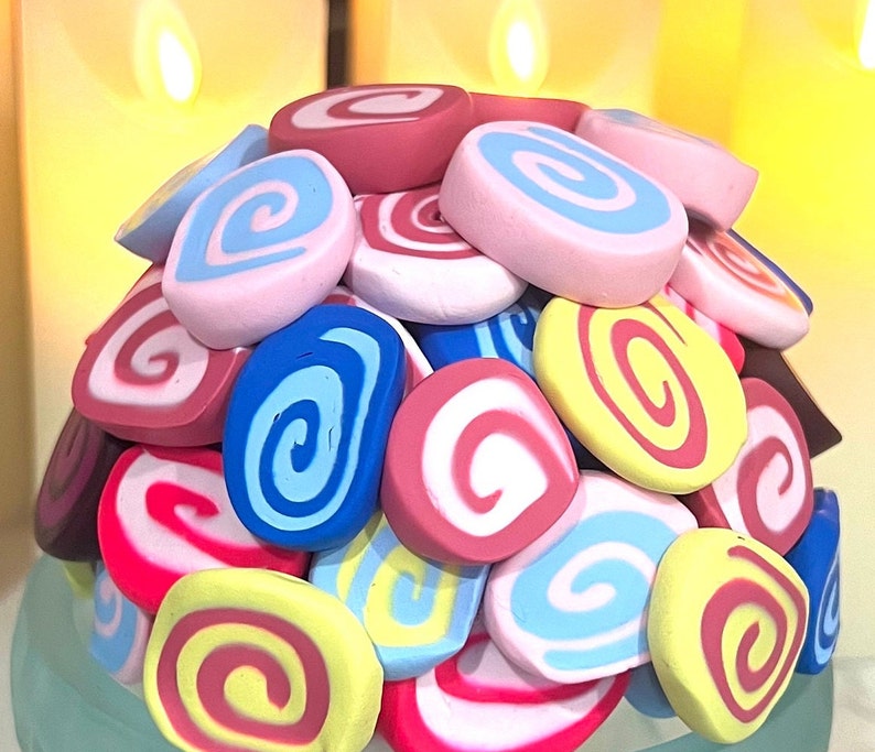 May include: A colorful assortment of swirl-patterned, candy-like decorations in pink, blue, yellow, and red.