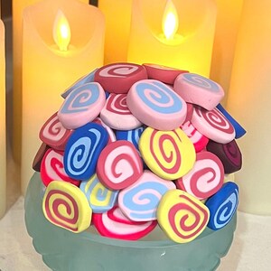 May include: A collection of colorful, swirl-patterned, clay-like candies in pink, blue, yellow, and red.