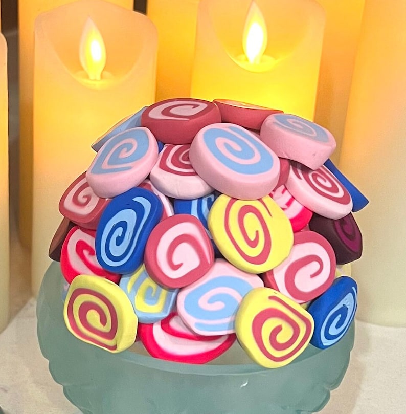 May include: A collection of colorful, swirl-patterned, clay-like candies in pink, blue, yellow, and red.