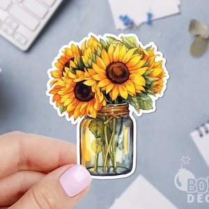 May include: A watercolor illustration of a bouquet of sunflowers in a clear glass jar with a brown twine bow. The sunflowers are yellow with dark brown centers and green leaves.