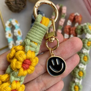 May include: A green, yellow, and orange crocheted keychain with a gold metal ring and a black smiley face charm.