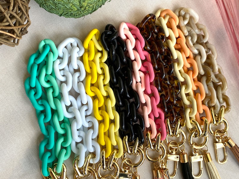 May include: A set of colorful plastic chain links with gold clasps. The chains are in shades of green, white, yellow, black, pink, orange, and beige.
