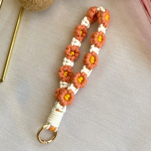May include: A peach and yellow crocheted flower keychain with a gold metal ring.