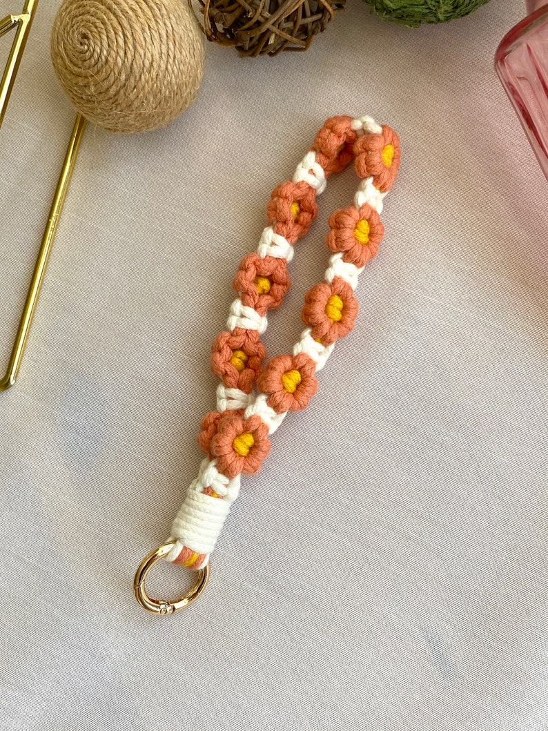 May include: A peach and yellow crocheted flower keychain with a gold metal ring.