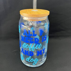 May include: A clear glass tumbler with a bamboo lid and a clear plastic straw. The tumbler has a blue and white design with the text "All I need is coffee and my dog".