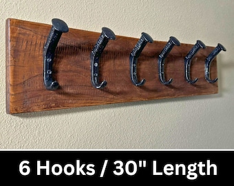 May include: A wooden wall-mounted coat rack with six black metal hooks. The rack is 30 inches long and has a rustic brown finish.