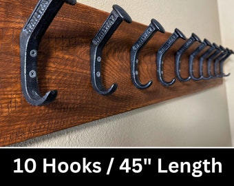 May include: A wooden coat rack with 10 black metal hooks. The hooks are shaped like bent nails and have the word "Railway" stamped on them. The rack is 45 inches long. 10 Hooks / 45" Length