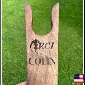 May include: A personalized wooden boot jack with the text "RCI" and "COLIN" engraved on it. The boot jack is made in the USA.