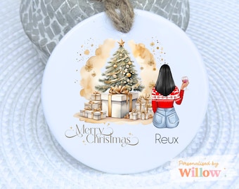 May include: Round white Christmas ornament with a watercolor design. The ornament features a Christmas tree, wrapped gifts, and a woman holding a glass of wine. The words "Merry Christmas" and a name are written on the ornament.