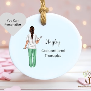 May include: White round ceramic ornament with a drawing of a woman in scrubs and the text "Hayley Occupational Therapist".