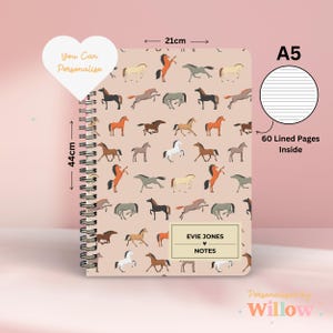 May include: An A5 notebook with a spiral binding. The cover features a repeating pattern of colourful horses on a light pink background. The notebook has 60 lined pages and includes the text "EVIE JONES" and "NOTES".