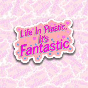 May include: Pink sticker with the text "Life in Plastic, It's Fantastic" in a pink, yellow, and blue font. The sticker is decorated with pink hearts and blue stars.