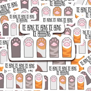 May include: A set of four cat paw stickers with the text "Toe Beans Toe Beans Toe Beans Toe Beieans". The stickers feature different colored paw pads and stripes, including gray, white, orange, and black.