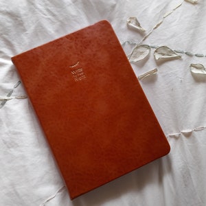 May include: A brown leather-bound journal with the words "Write the Story Right" embossed in gold on the front cover.