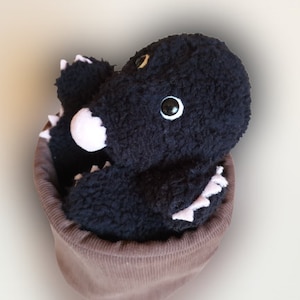May include: A black plush mole toy with pink claws and white eyes, sitting inside a brown fabric pot.