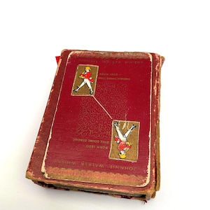 May include: A vintage red and gold Johnnie Walker Whisky booklet. The cover features the text "Johnnie Walker Whisky" and "Born 1820 Still Going Strong." Two illustrations of a man in a red coat are on the cover.