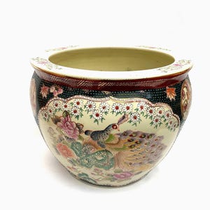 Pode incluir: Um grande vaso redondo de cerâmica com uma abertura larga. O vaso apresenta um design detalhado e colorido de um pavão e outras aves em meio a flores e folhagens. A borda é decorada com padrões florais.