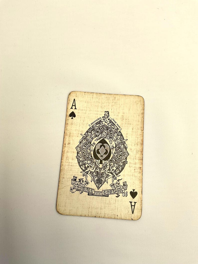 May include: Vintage playing card, the Ace of Spades, with a detailed black and white illustration. The card features the word "A" in the corners and an ornate central design with text that reads "Goodall London". The card has a distressed, aged appearance.