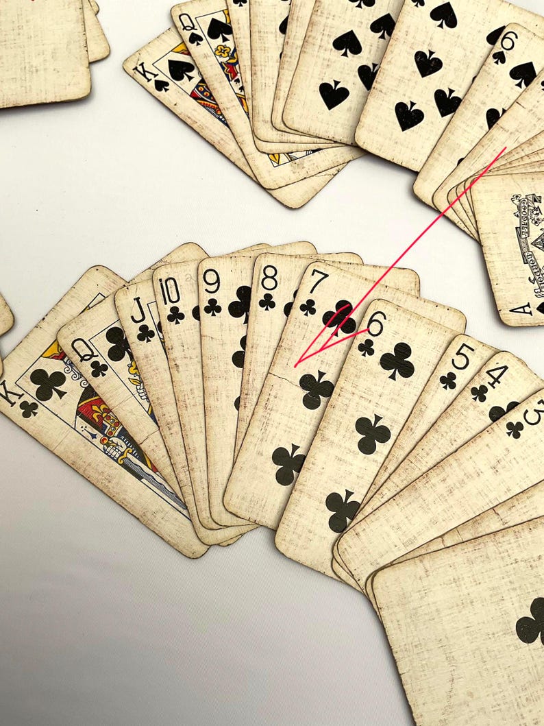 May include: A collection of vintage playing cards, featuring the suits of clubs and spades. The cards have a worn, antique appearance with visible wear and tear. The image showcases various numbered cards, including the six, seven, eight, nine, and ten of clubs.